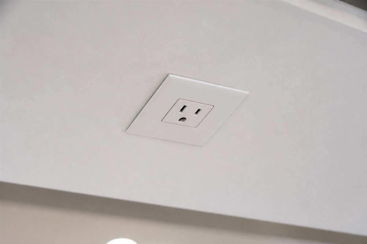 White ceiling power outlet mounted through a reinforced trim plate